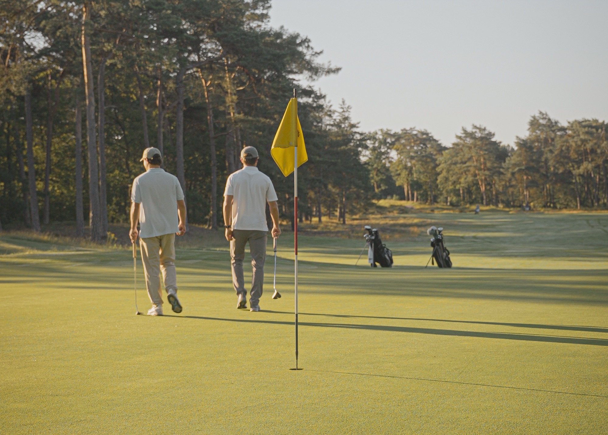 Guus and Sergi walking off the green at golden hour